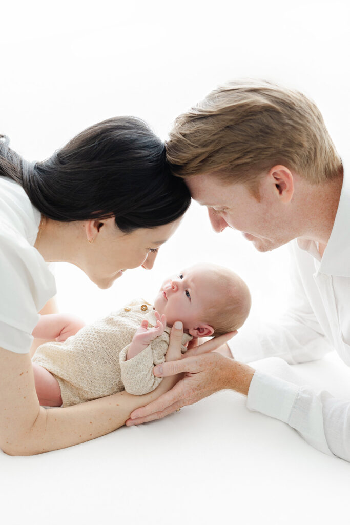 first time parents leaning over newborn baby boy, NYC newborn photographer, Heirloom by Melissa Photography Flatiron