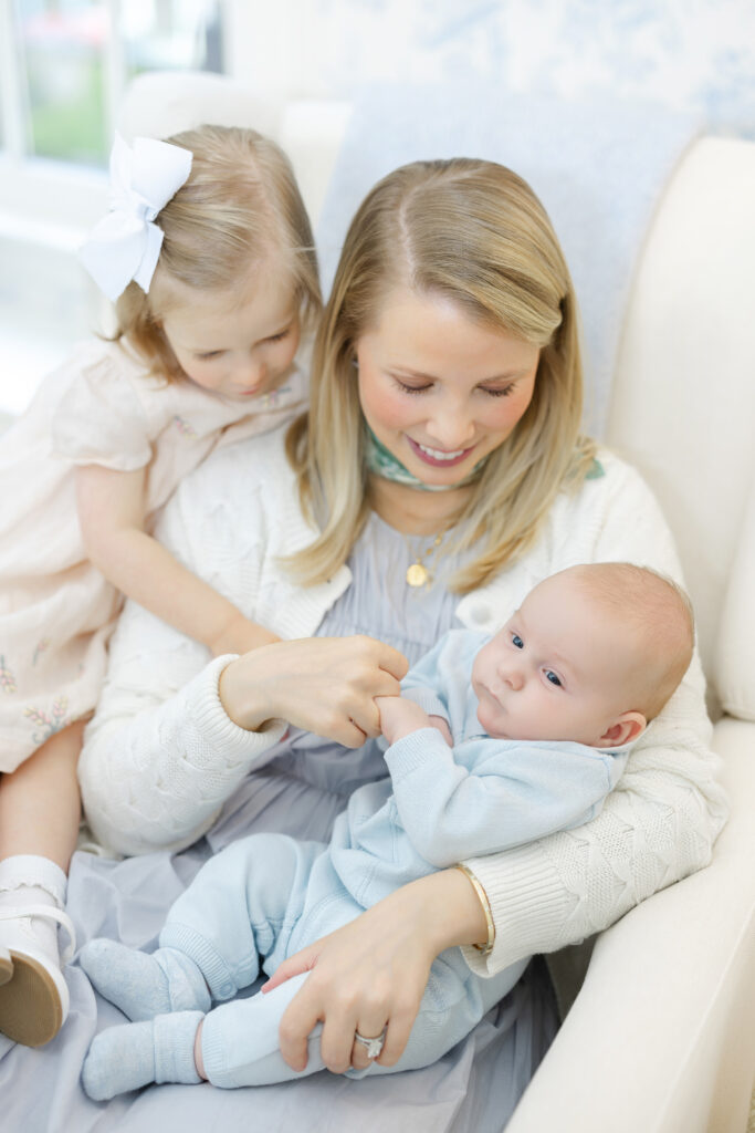 Mother holding newborn baby in softly lit nursery during NYC in-home newborn family session
