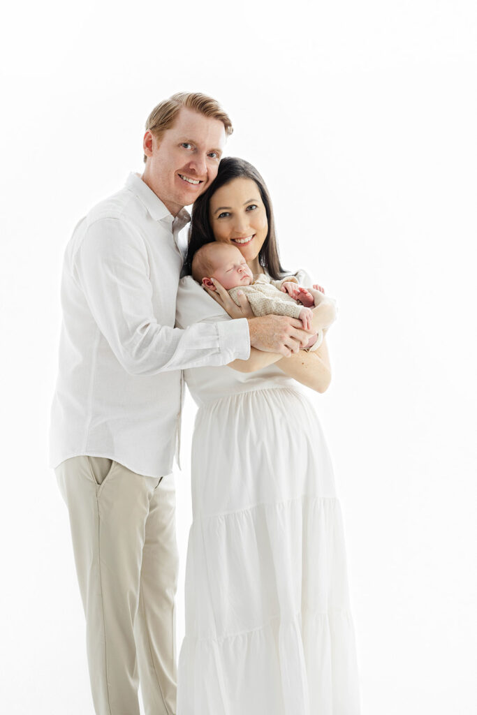 mom holding sleeping newborn against her cheek dad smiling behind, NYC newborn photography, Heirloom by Melissa