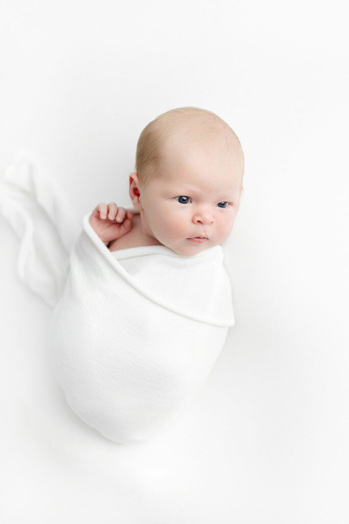 NYC newborn photographer, newborn baby boy awake wrapped in white swaddle, Heirloom by Melissa Photography Flatiron studio Manhattan