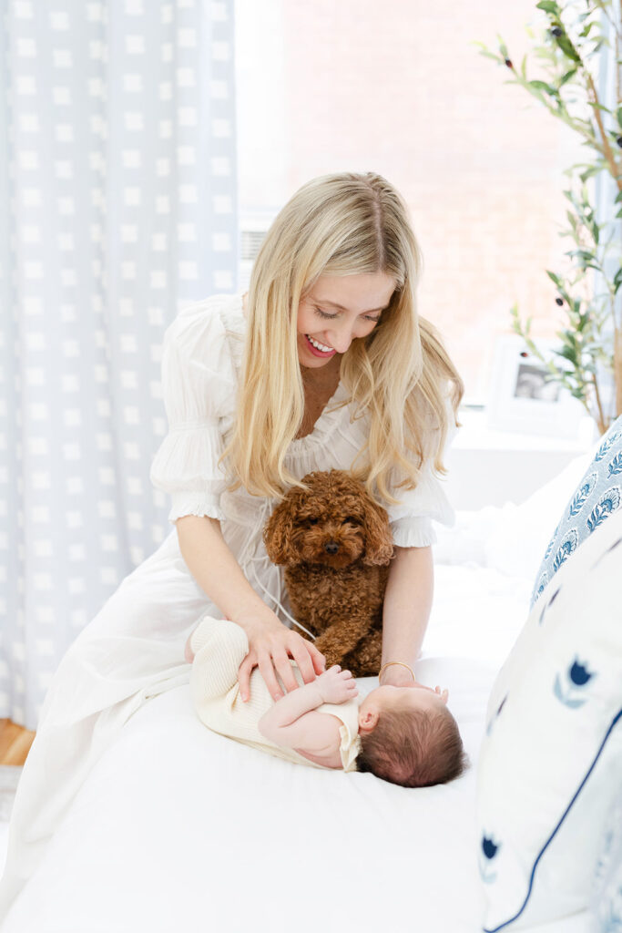 Mother holding newborn baby with dog resting nearby, NYC baby photographer, Heirloom by Melissa