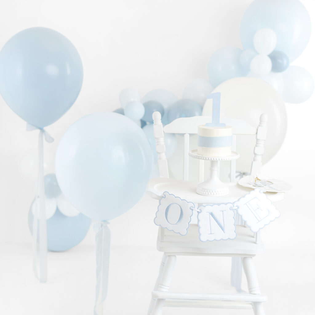 NYC cake smash photos with blue balloon garland and vintage high chair at Heirloom by Melissa, Flatiron Manhattan studio