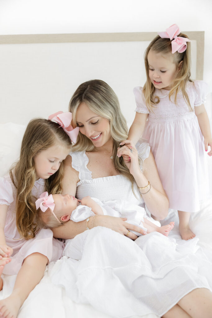 Mom with daughters in pink nursery documented by New York newborn photographer Heirloom by Melissa