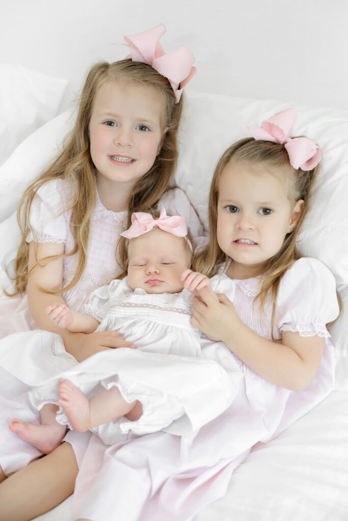 Sisters in pink Feltman Brothers dresses with baby, New York newborn photographer Heirloom by Melissa