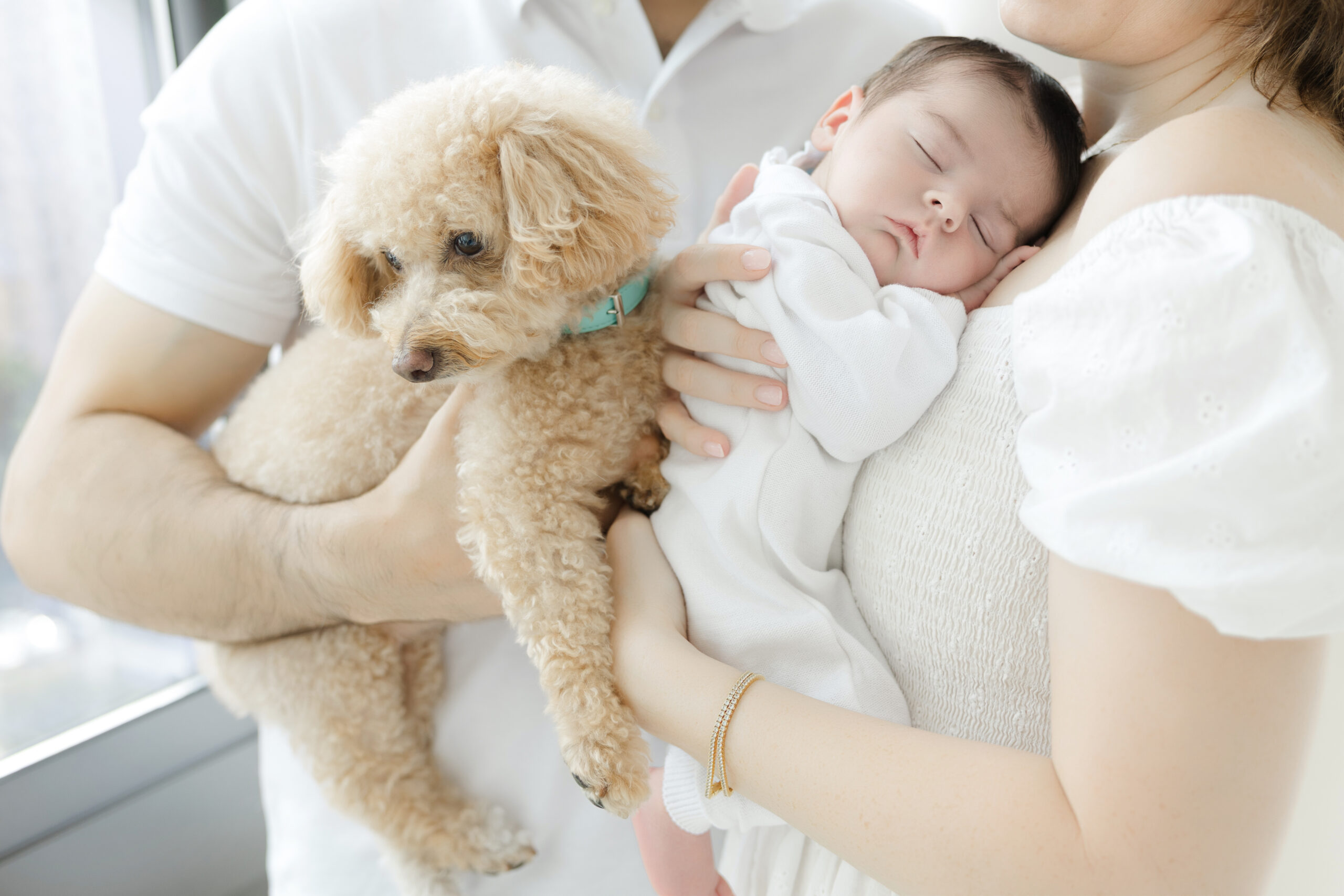Mother holding her sleeping newborn beside the family dog