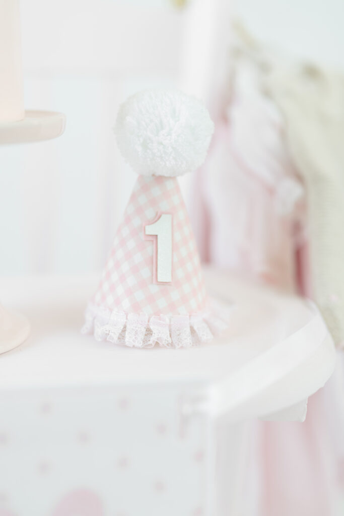 Pink gingham first birthday hat with a white pom-pom