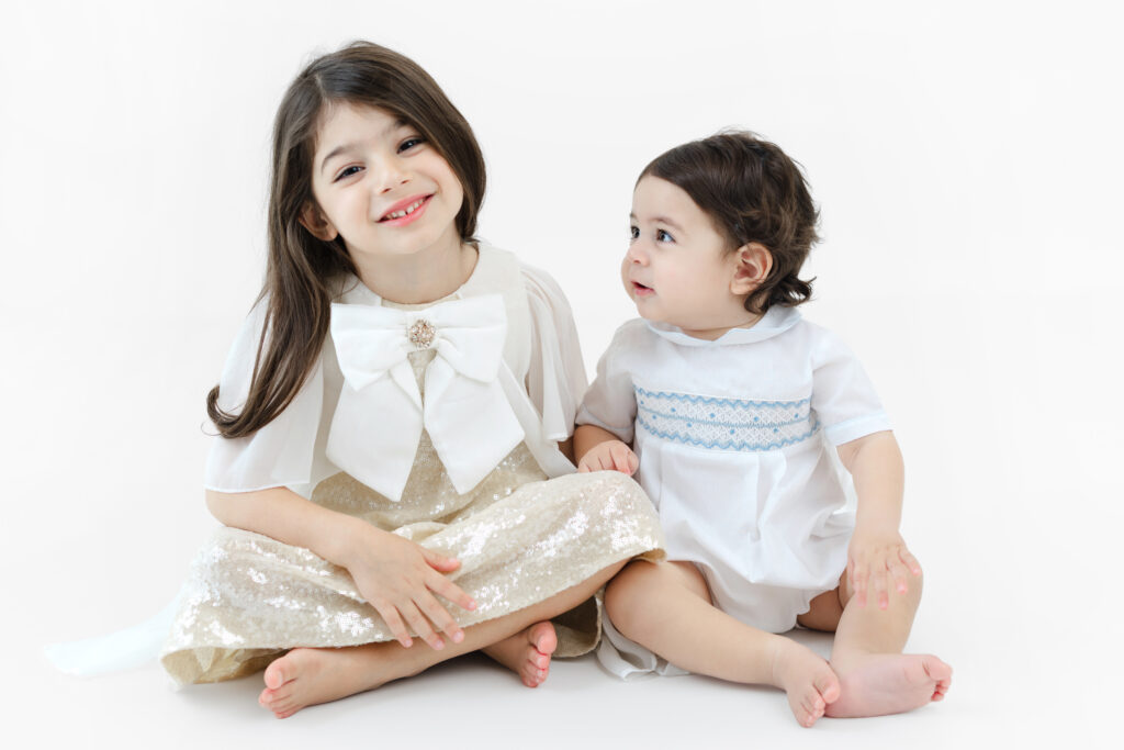 Soren sitting beside his older sister at a first birthday studio session