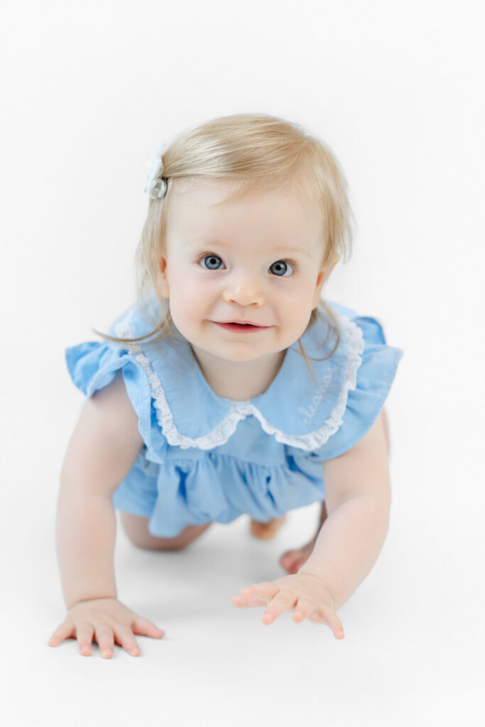 Eleanor smiling in a blue outfit against a white backdrop