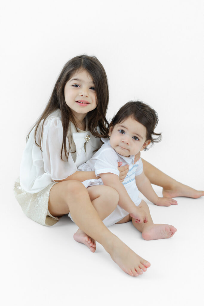 sibling portrait against a white studio backdrop