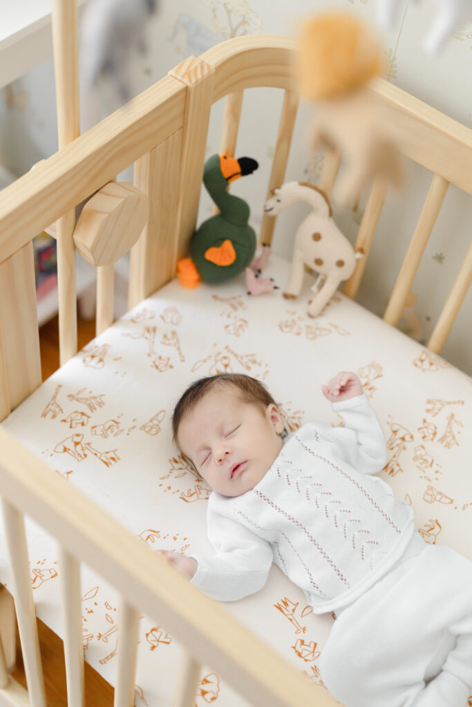 Newborn baby lying in his crib beneath a nursery mobile