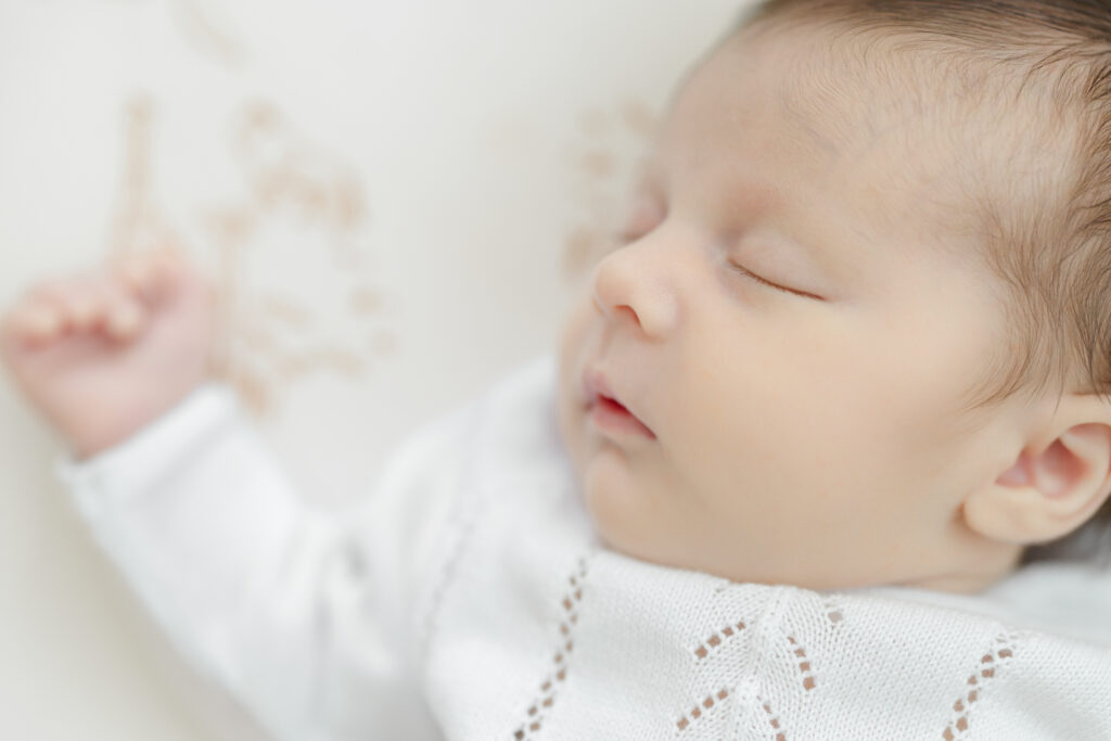 Close portrait of a sleeping newborn in a white outfit
