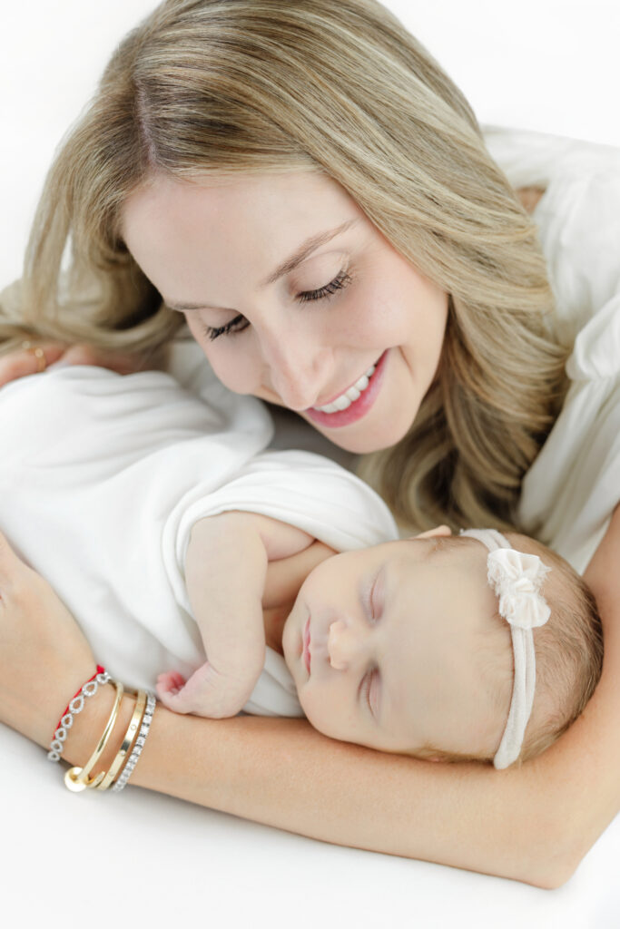 Mother leaning close to her sleeping newborn baby at the studio