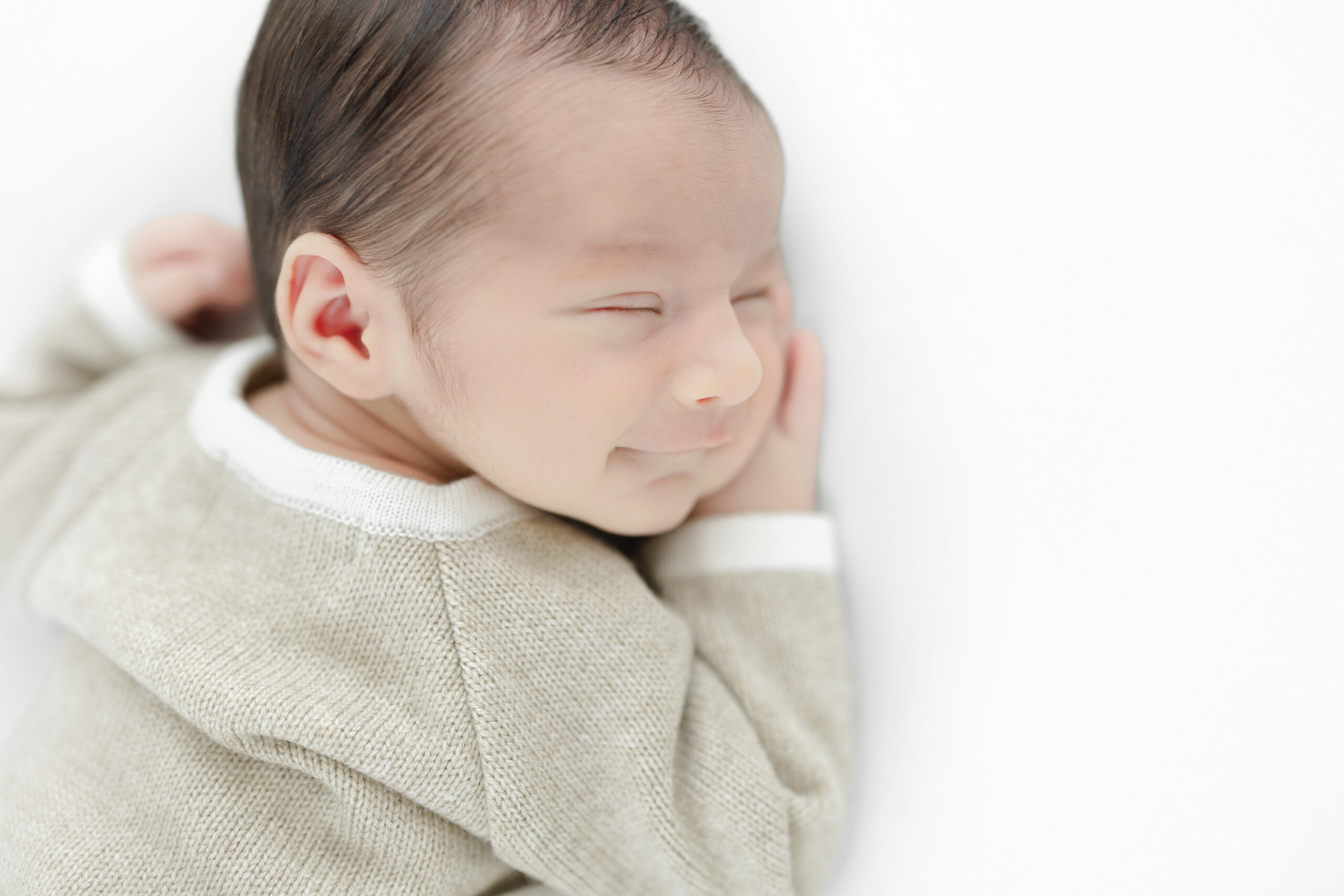 Close portrait of a sleeping newborn baby boy wearing a beige outfit
