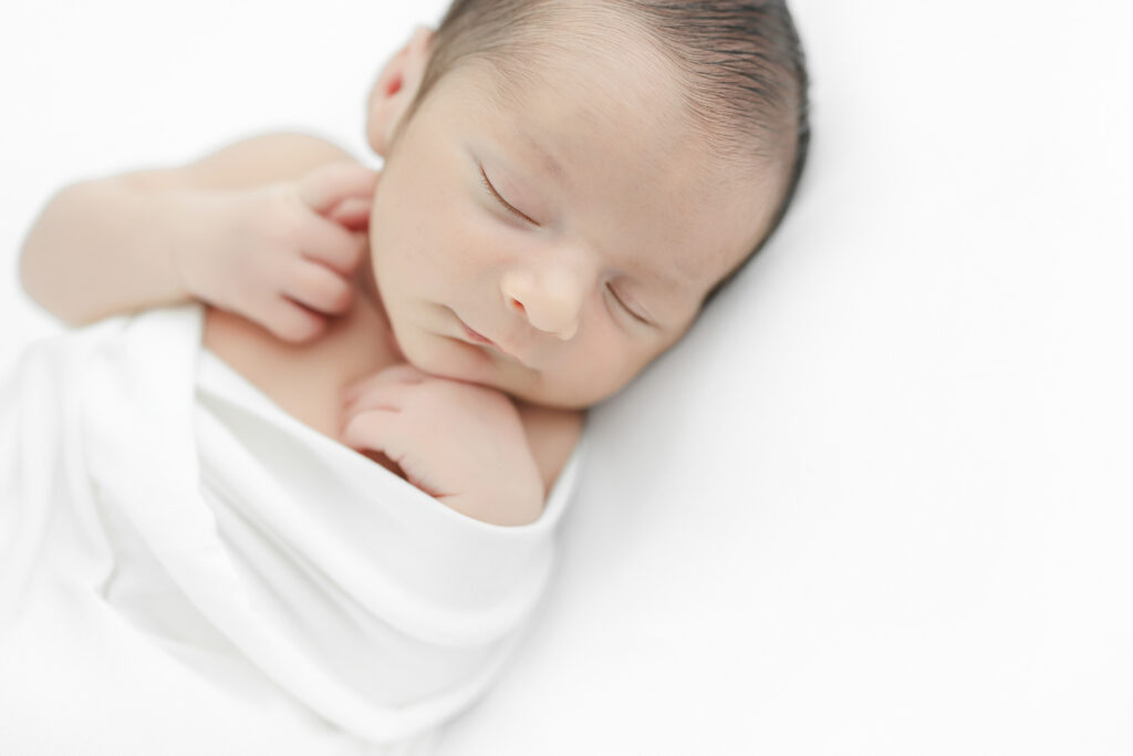 Sleeping baby boy swaddled newborn session