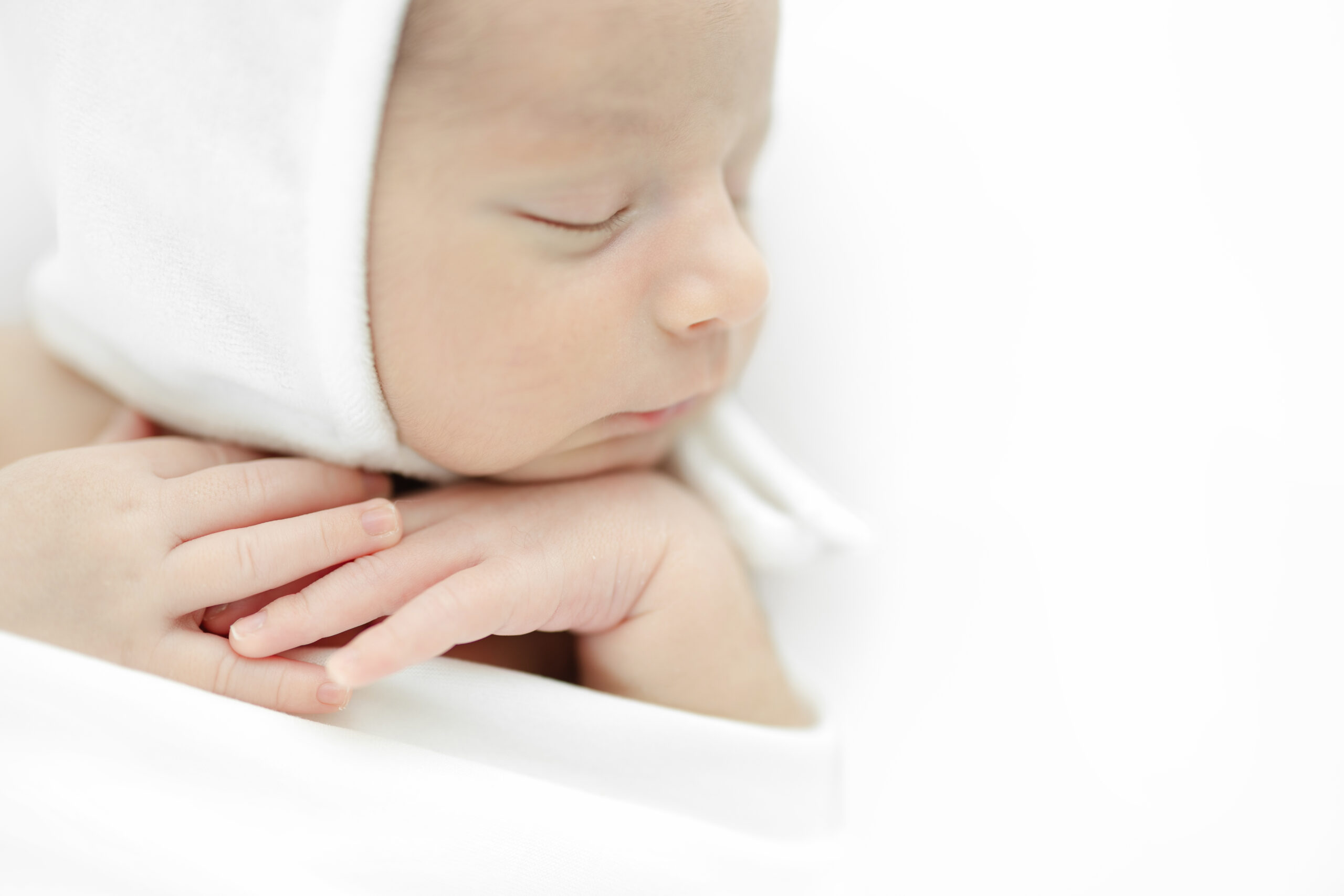 Sleeping baby boy posed naturally on white in a New York City newborn studio