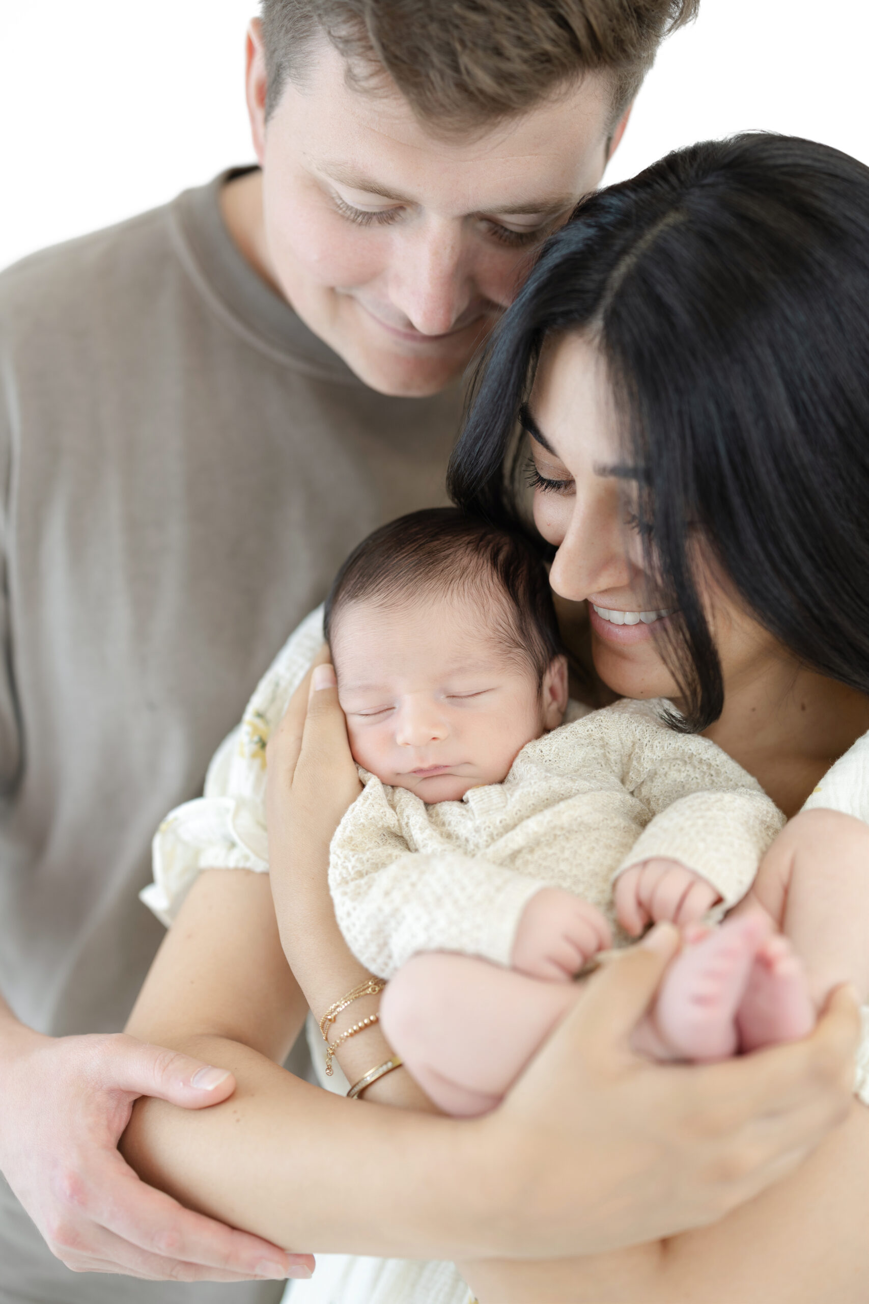 Parents cuddling their newborn baby boy during a timeless family portrait session