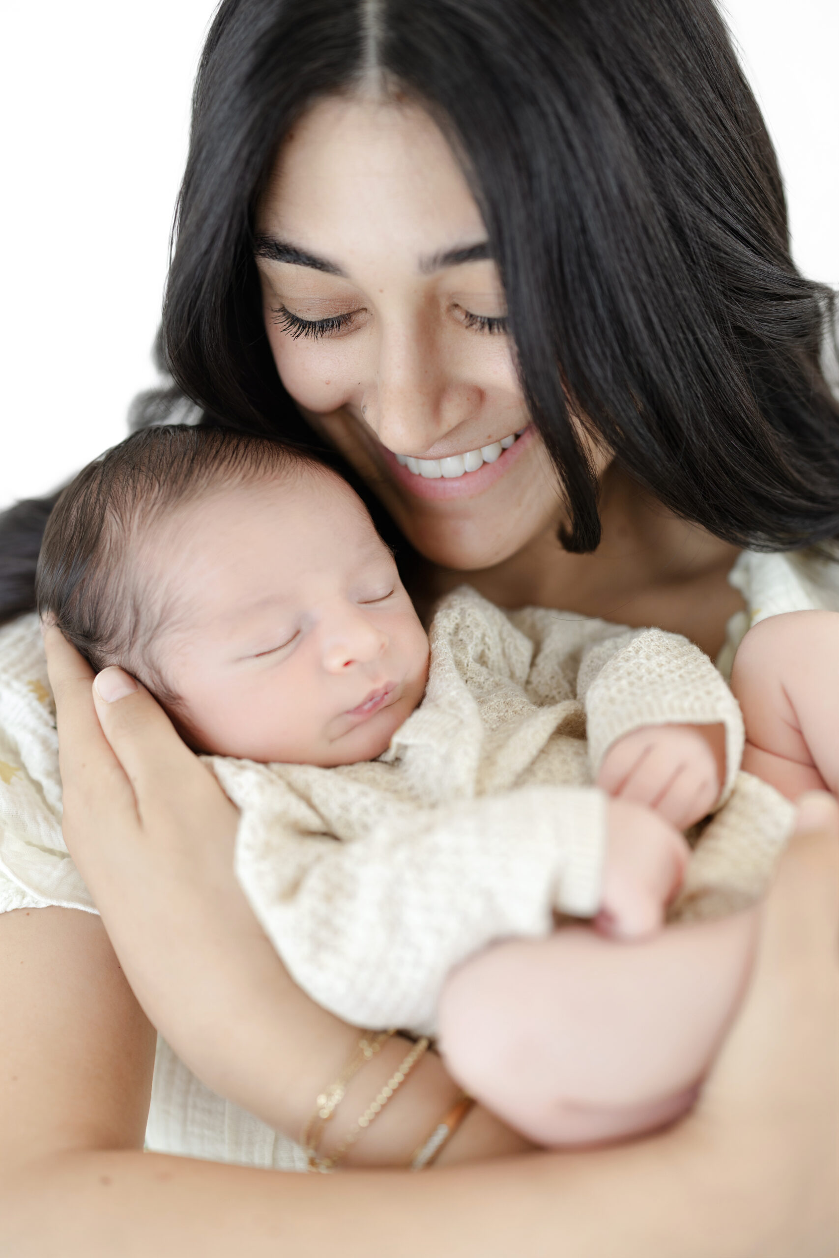 Mother smiling down at her sleeping baby boy during an NYC newborn session