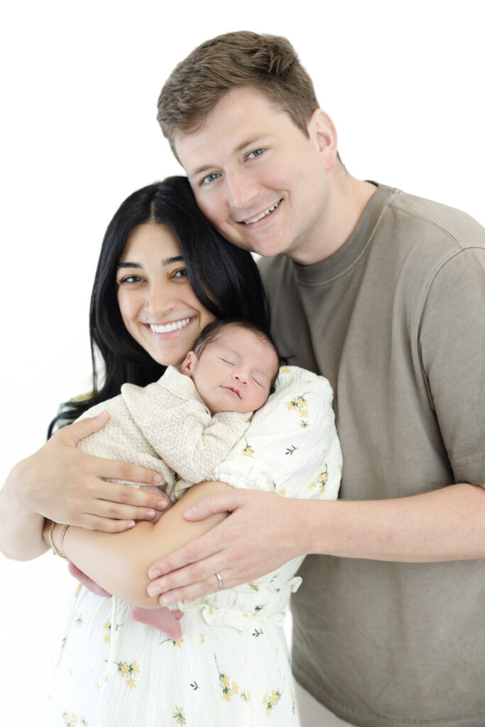 New parents holding their baby boy during a light-filled NYC newborn photography session
