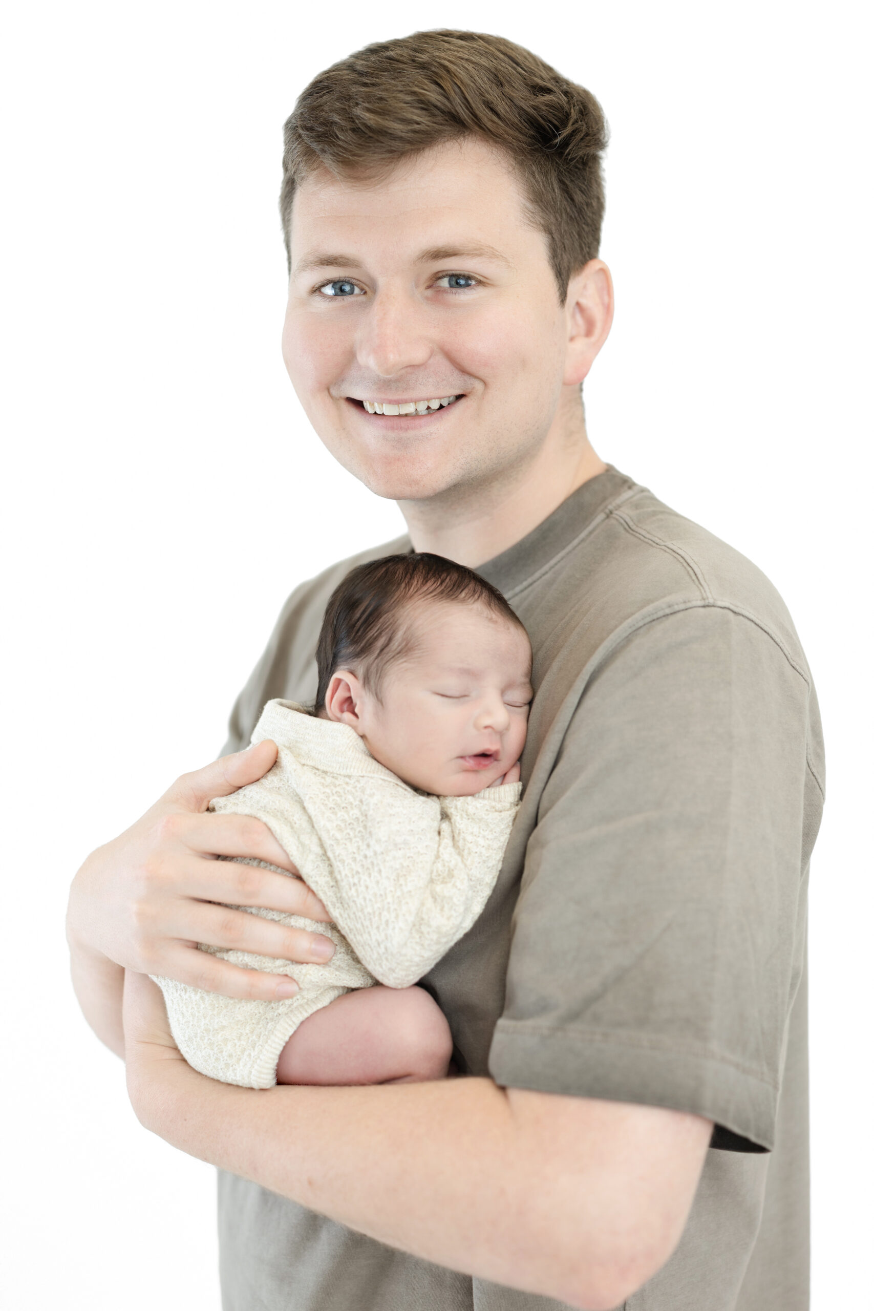 Father holding his newborn son against a clean white studio background