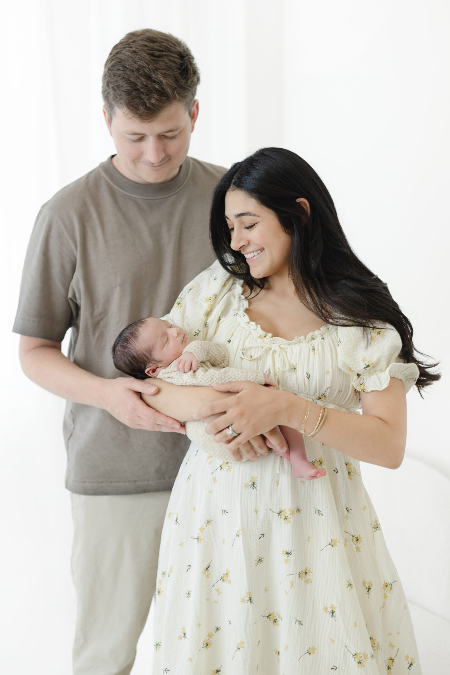 Mother and father smiling over their newborn son during a studio session in NYC