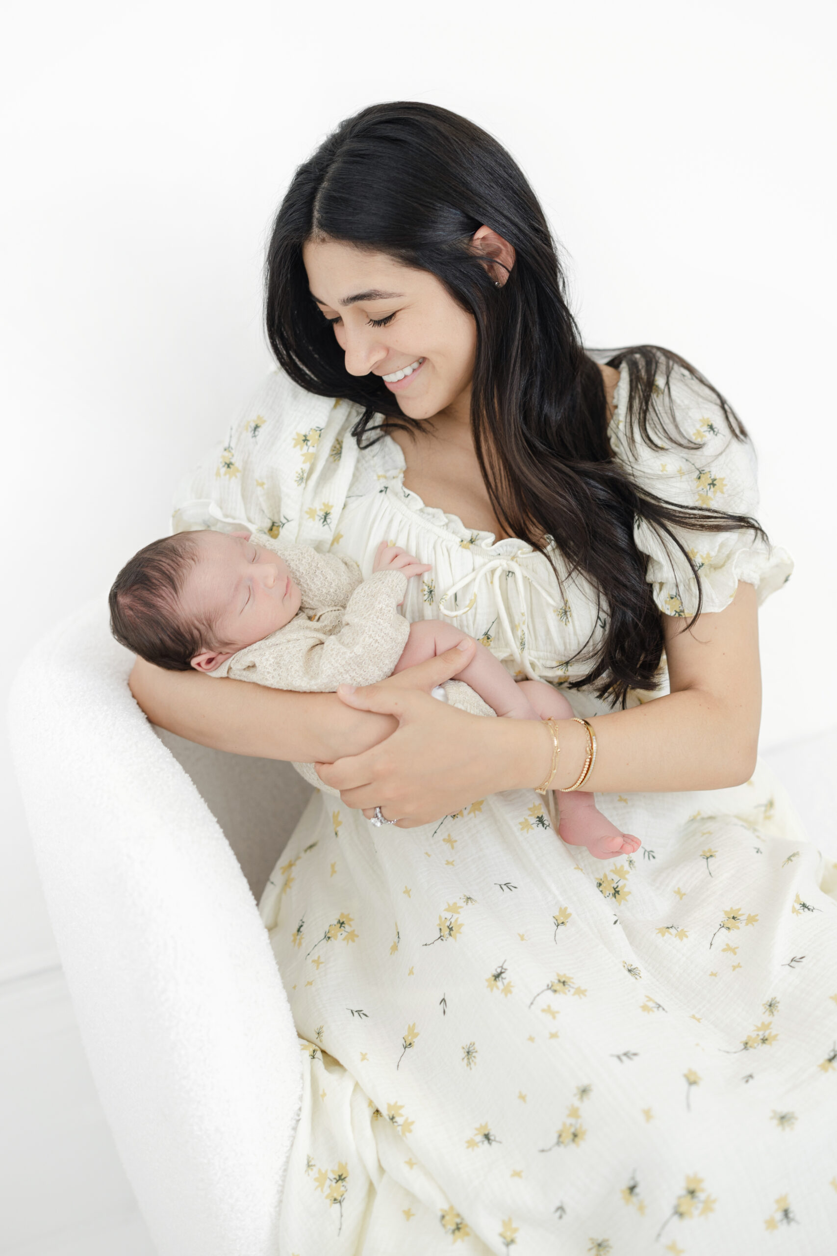 Mother holding her newborn son in a soft light-filled studio portrait