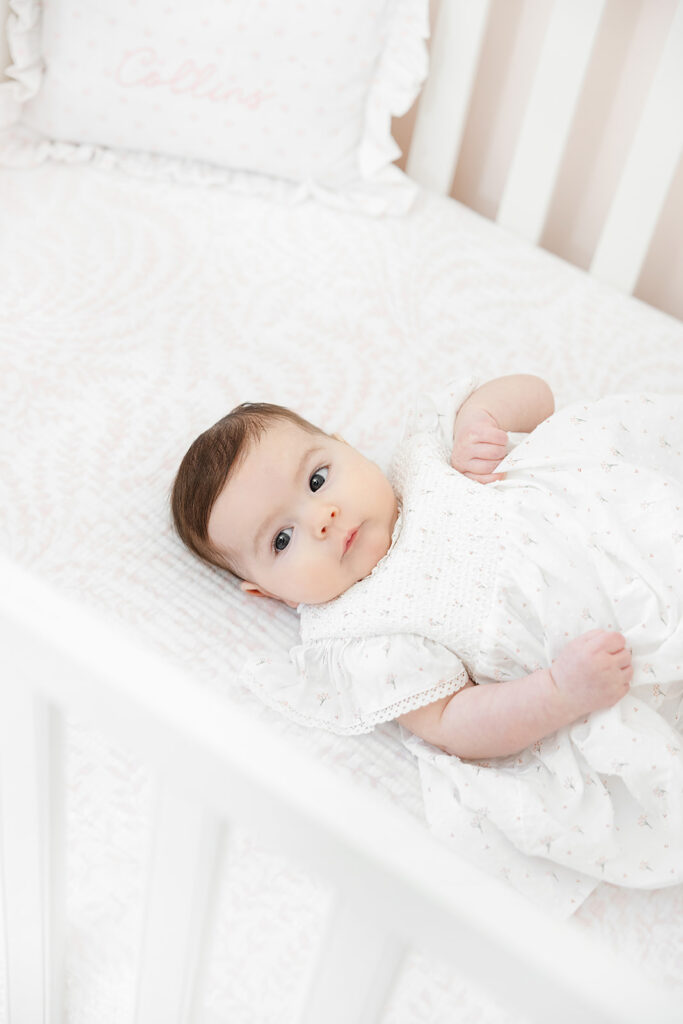Three-month-old baby girl sitting safely with support during an in-home photo session