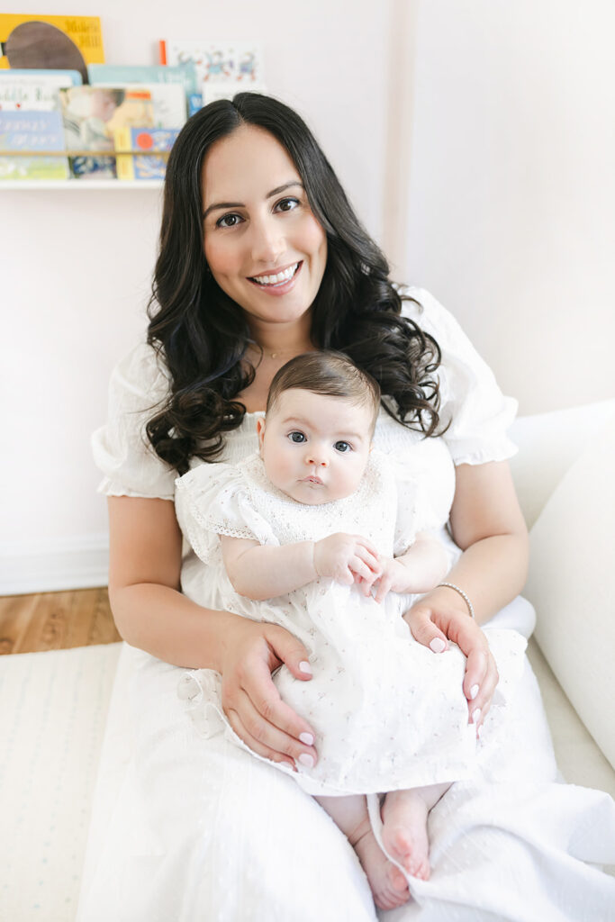 Mother holding her three-month-old daughter beside the crib in their Manhattan home