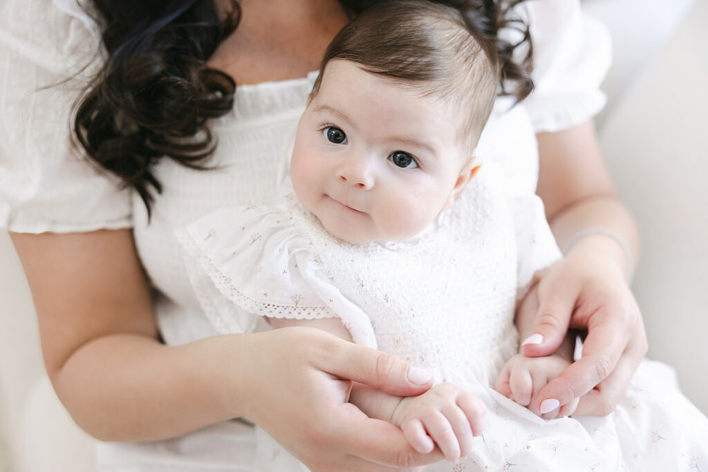 Three-month milestone portrait of a baby girl in a white dress