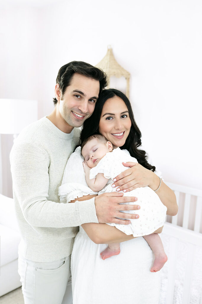 Sleeping three-month-old baby girl cuddled against her mother at home