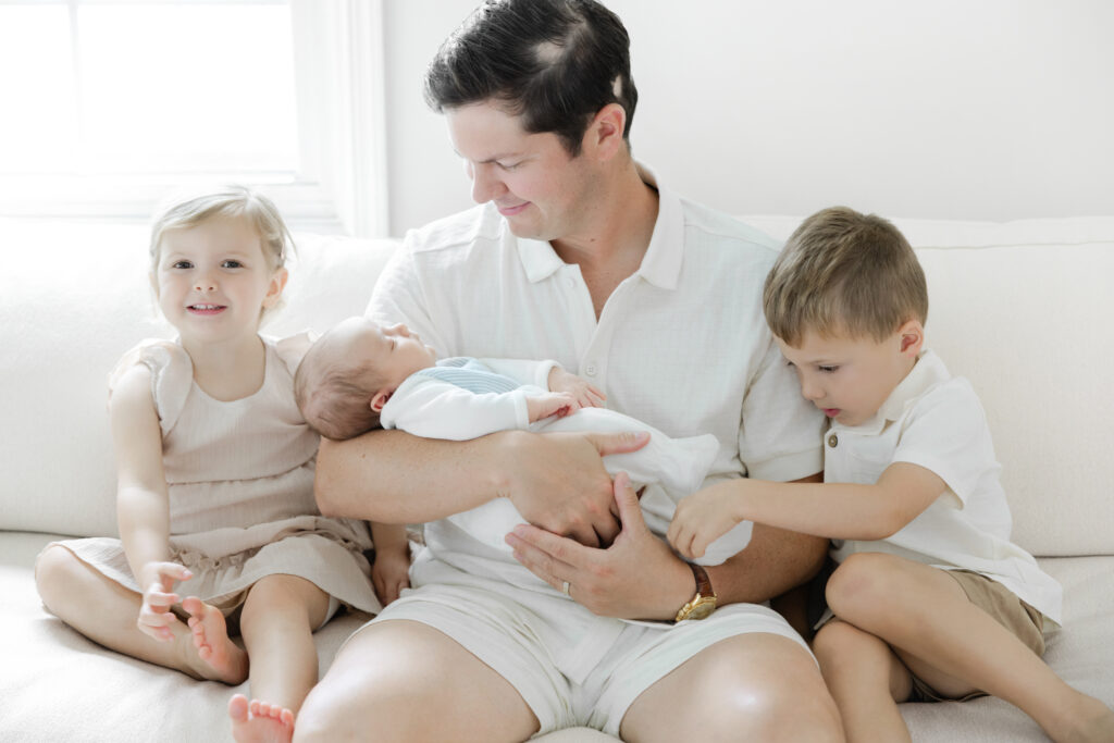 Father holding his newborn baby with two older siblings