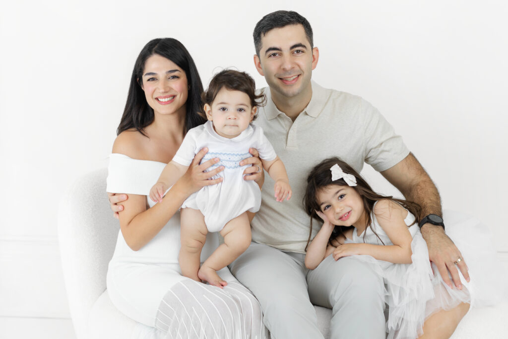 Parents posing with Soren and his older sister against a white backdrop