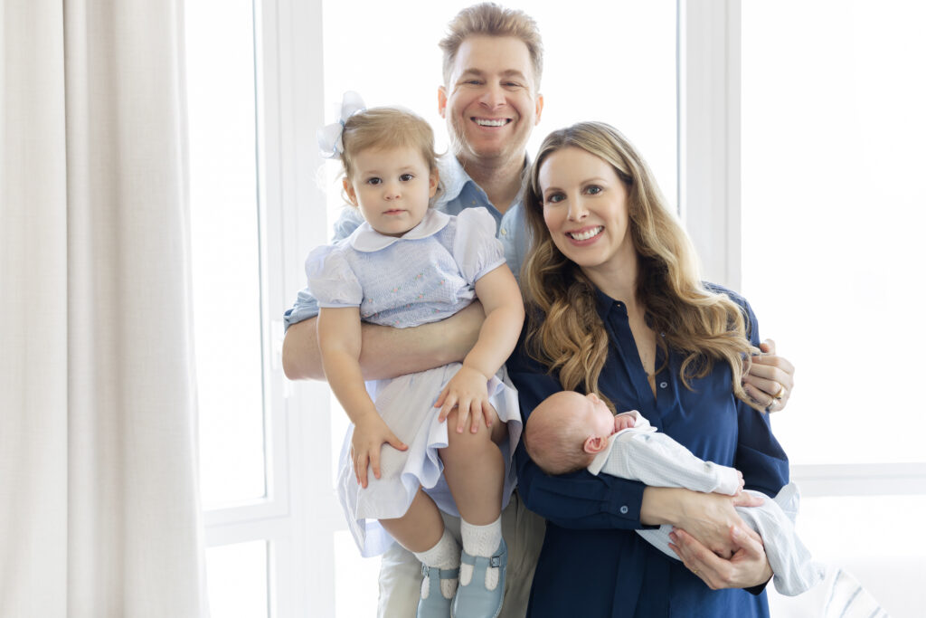 Family of four by the window during an Upper East Side in-home newborn photography session