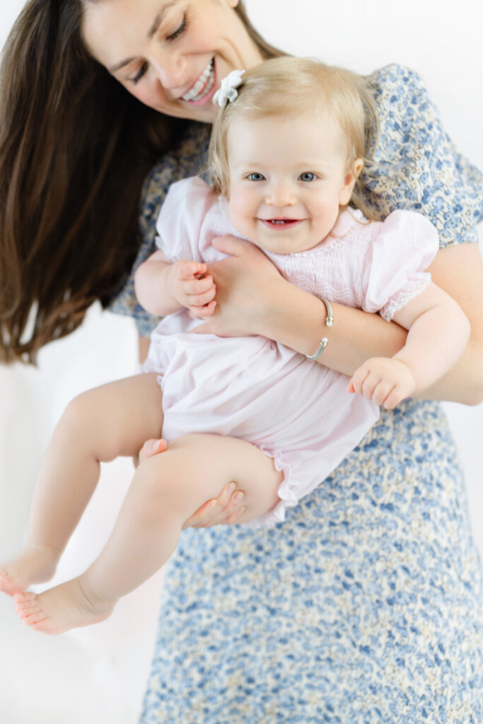 Eleanor smiling while sitting in her mother’s arms