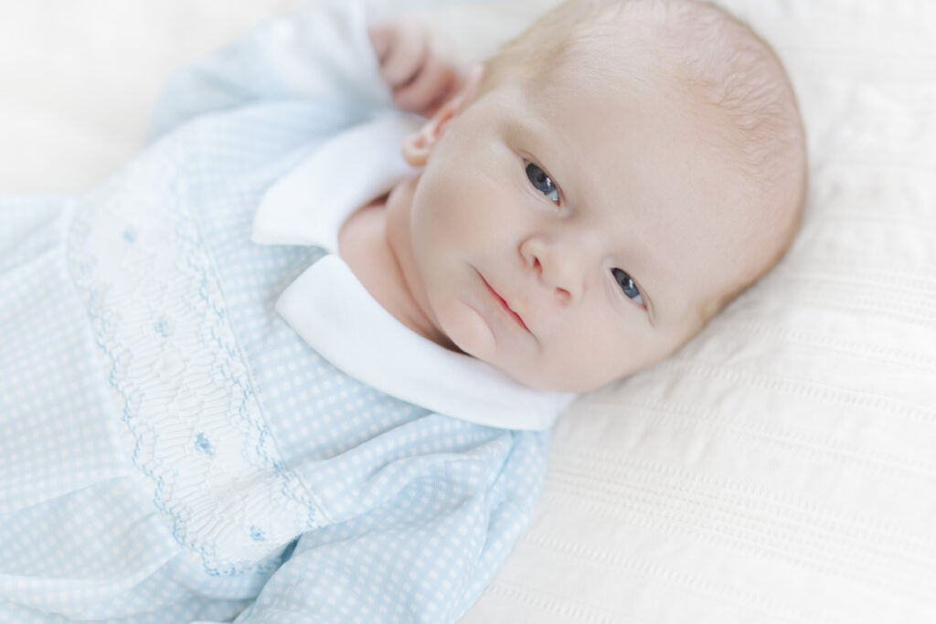 Close portrait of a newborn baby wearing a pale blue outfit