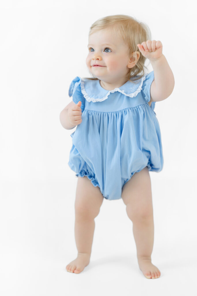 Eleanor smiling in a blue outfit against a white backdrop