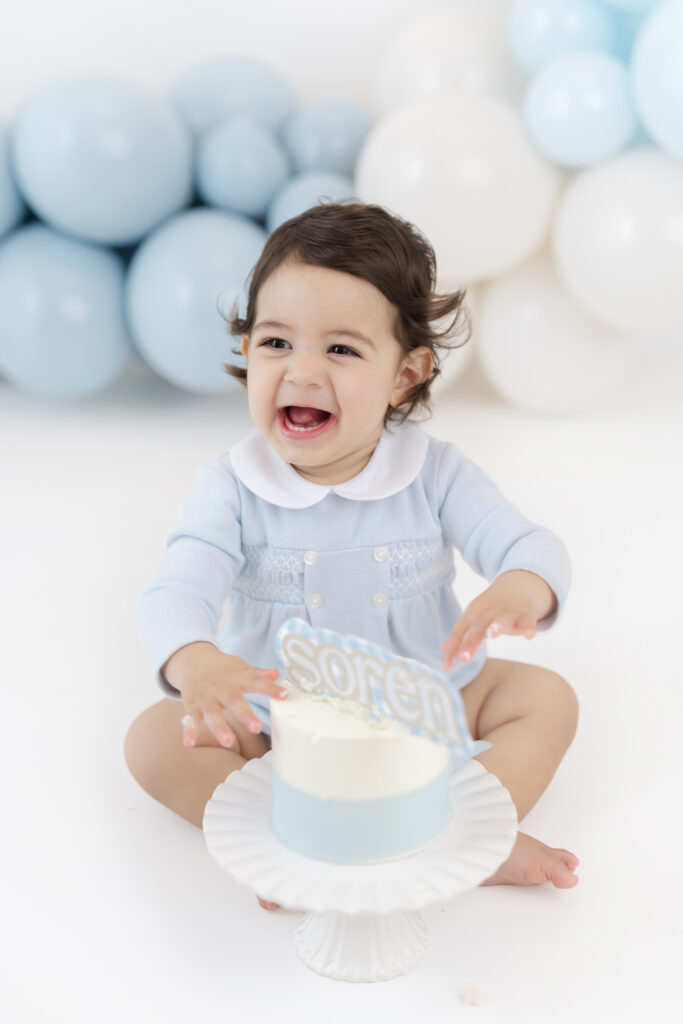 Soren exploring his white birthday cake during a blue cake smash session