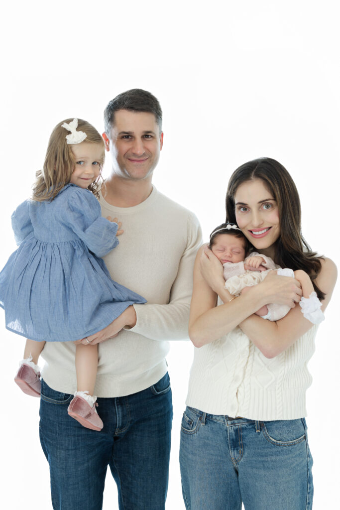Family of four standing together during an NYC studio newborn photography session