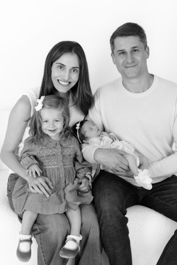 Black and white seated portrait of a family of four with their new baby