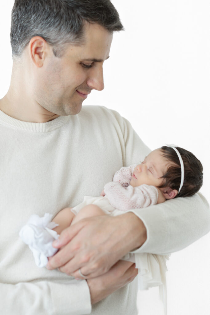 Father looking down at his sleeping newborn daughter in his arms