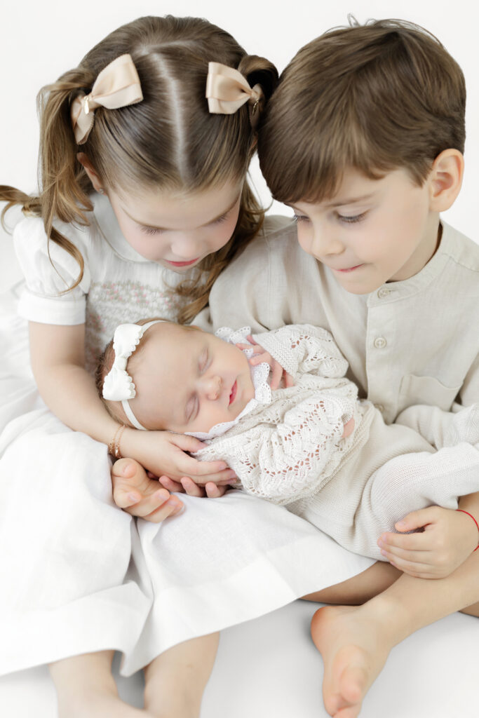 Older brother and sister looking at their newborn sister during an NYC studio session