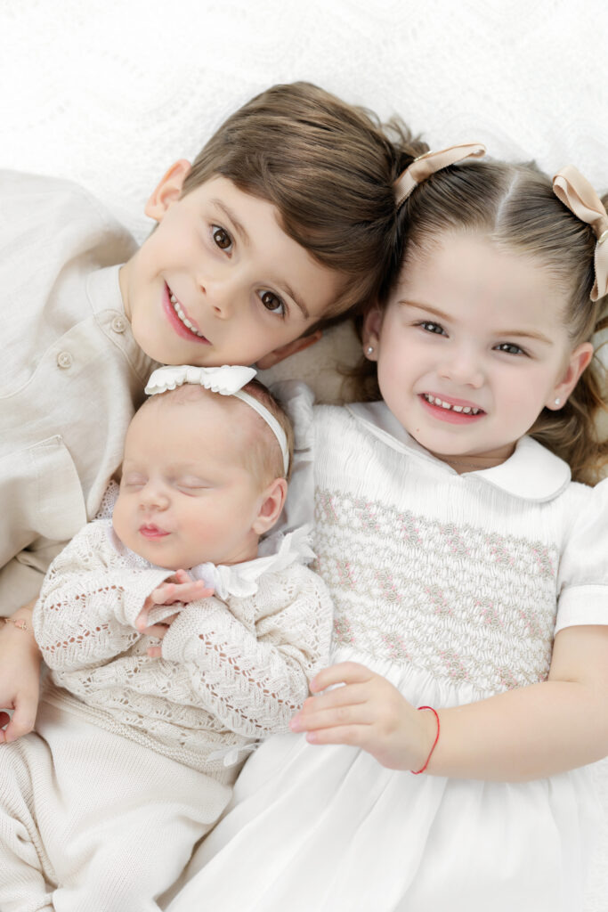 Brother and sister sitting close beside their newborn sister