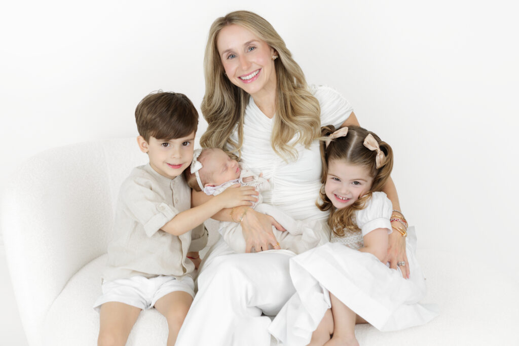 Mother sitting with her newborn baby and two older children at the studio