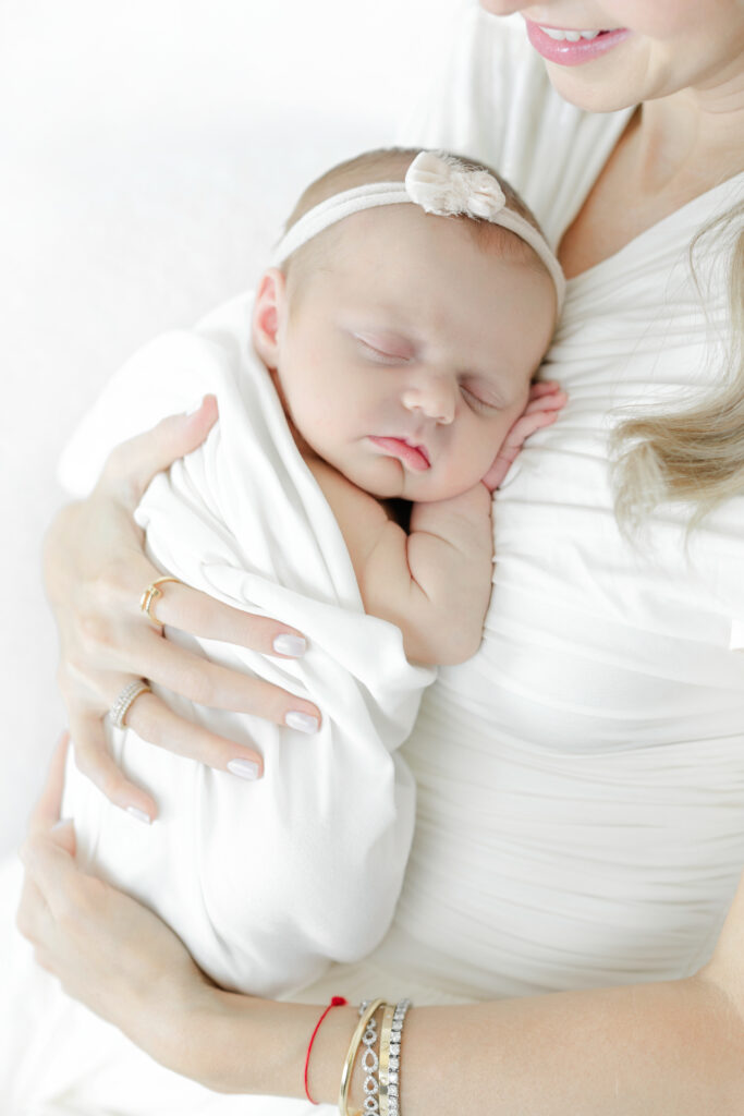Sleeping newborn resting against her mother’s chest in a white wrap