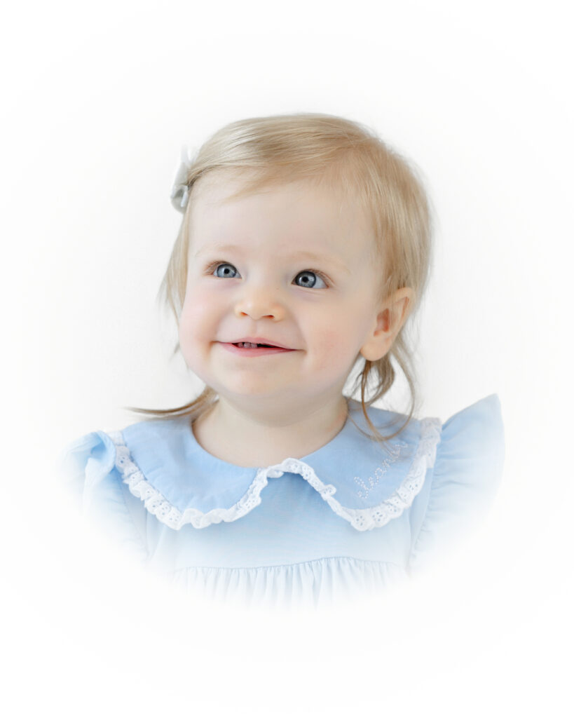 Softly faded studio portrait of Eleanor smiling in a blue outfit