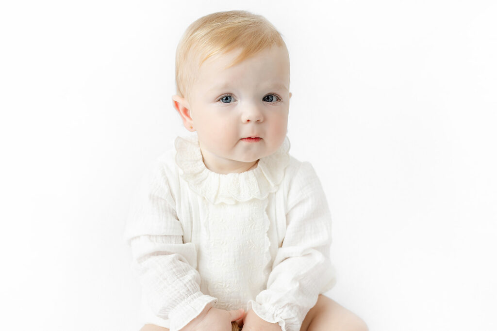 Baby girl wearing a classic white outfit for her NYC first birthday portraits
