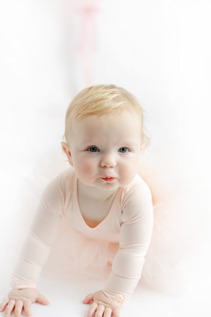 Baby girl crawling toward the camera during a soft pink NYC cake smash session