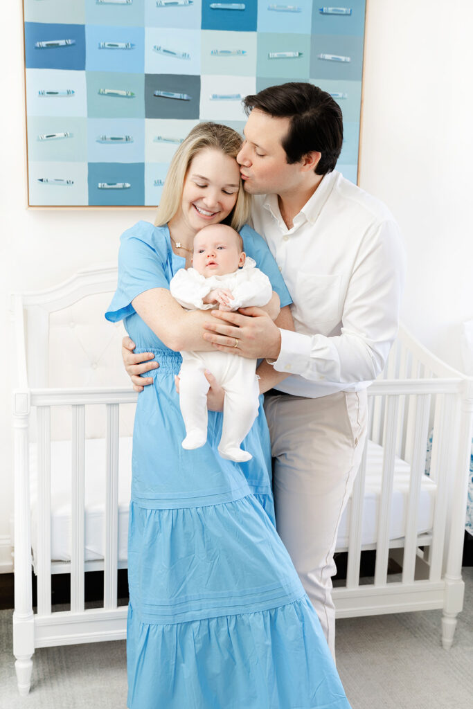 Parents cuddling their baby girl beside her crib during an Upper East Side newborn session